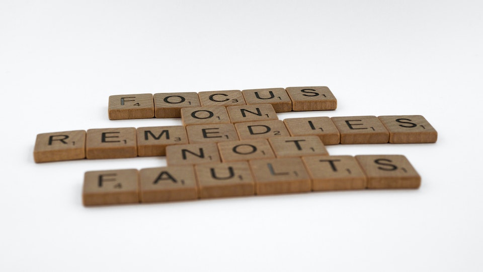 Scrabble pieces that spell out "focus on remedies not faults"