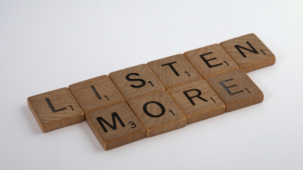 Scrabble pieces that spell out the phrase, "listen more"